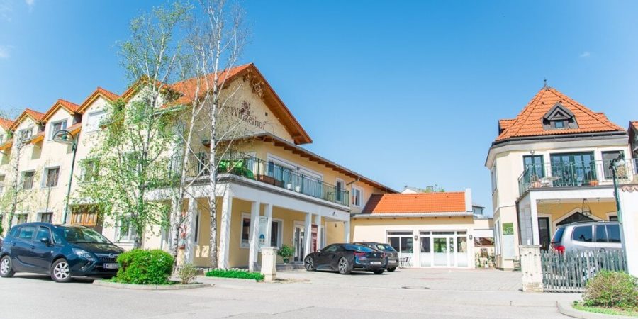 Modernes Gebäude in der Schweiz, das eine Ausbildung für freie Redner anbietet, mit Parkplätzen im Vordergrund und klarem blauen Himmel.