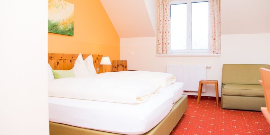 Gemütliches Hotelzimmer in der Schweiz mit Doppelbett, Sofa und Fenster, ideal für Redner-Workshops und Schulungen.