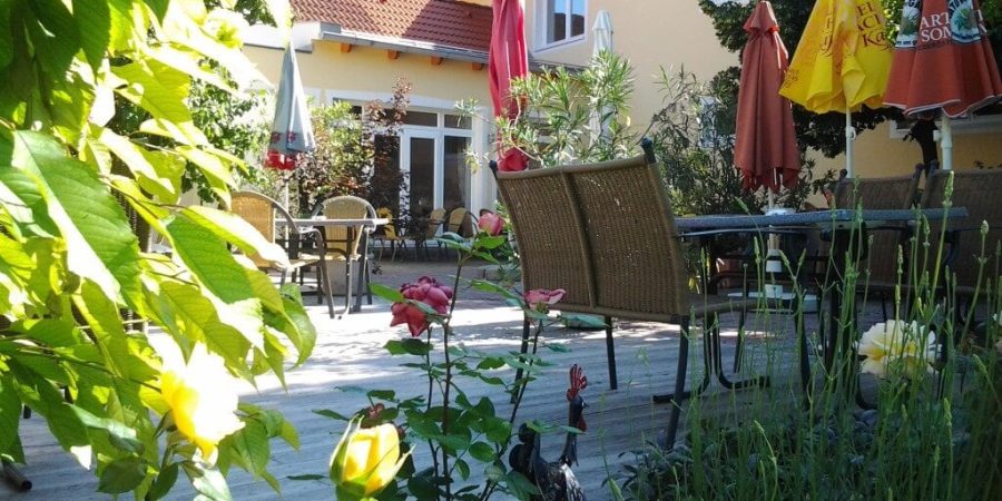 Garten im Freien mit Tischen, Stühlen und Sonnenschirmen, ideal für Redner-Training im Freien in der Schweiz.
