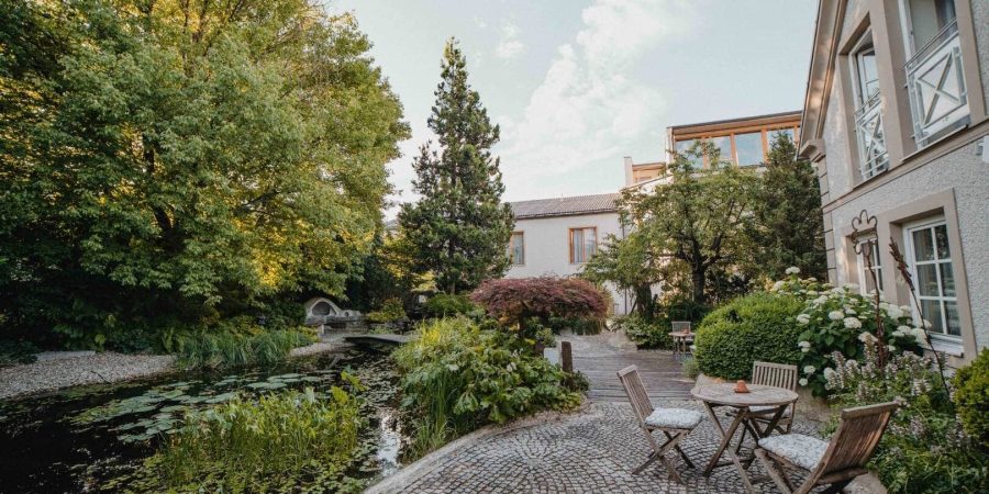 Charmanter Garten mit Sitzbereich und Wasserlauf, ideal für Redner-Training in der Schweiz.