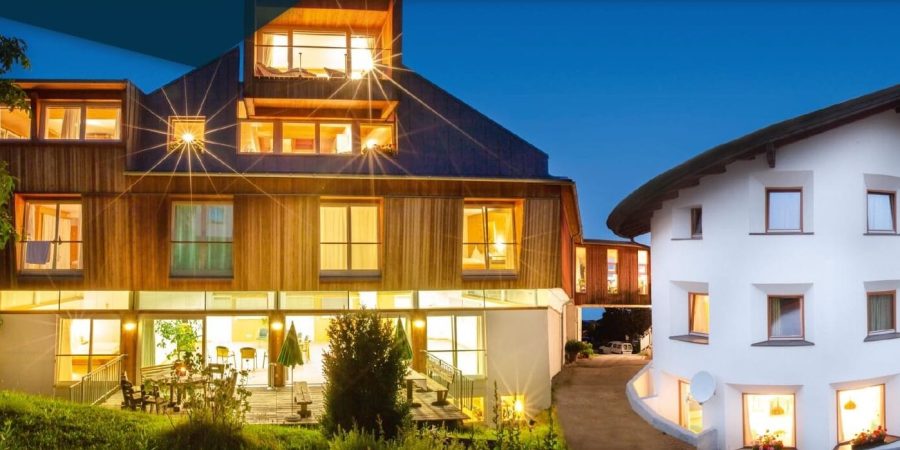 Modernes Gebäude in der Schweiz bei Nacht, das für die Ausbildung von freien Rednern genutzt wird, mit warmem Licht, Holzfassade und ansprechender Architektur.