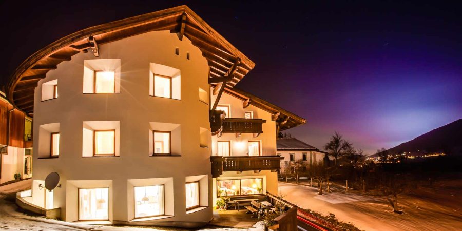 Modernes Haus in der Schweiz bei Nacht, ideal für Redner-Ausbildung, mit warmem Licht, umgeben von Schnee, zeigt professionelle Atmosphäre für Redner-Training.