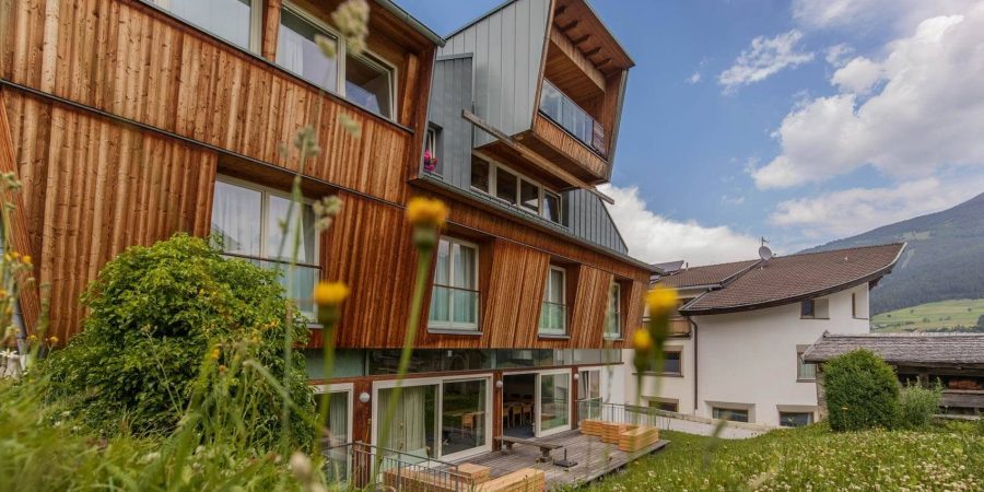 Modernes Holzgebäude in der Schweiz, Teil einer Rednerausbildung, umgeben von Natur, mit Blick auf Berge und Himmel.