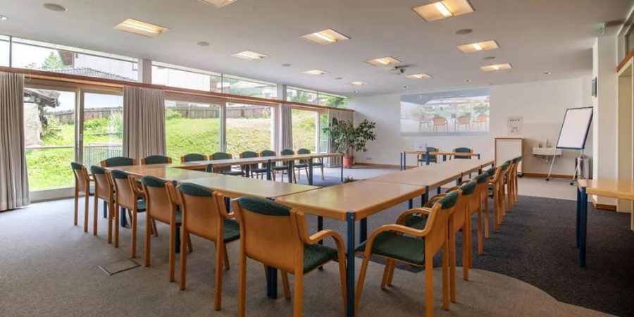 Moderner Seminarraum in der Schweiz für Rednerausbildung, mit großen Fenstern, Tischen und Stühlen, ideal für Schulungen und Workshops im Bereich freie Rednerausbildung.